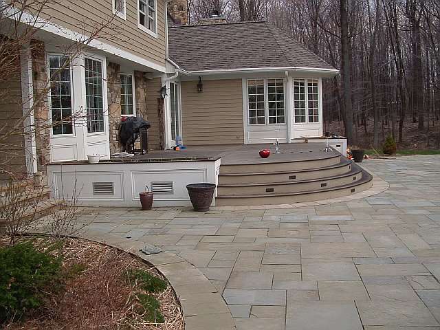 A Landscape Architect designed this large stonework patio which surrounds an elevated outdoor deck.